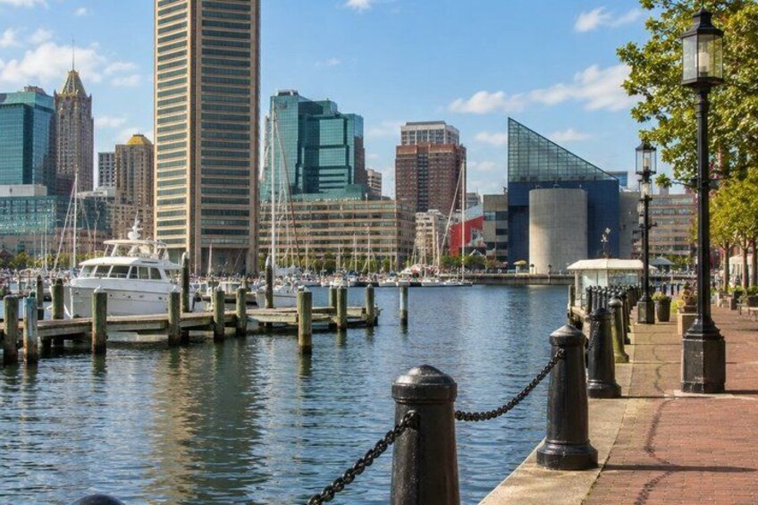 A waterfront cityscape with a marina, tall buildings, and a clear sky. 5