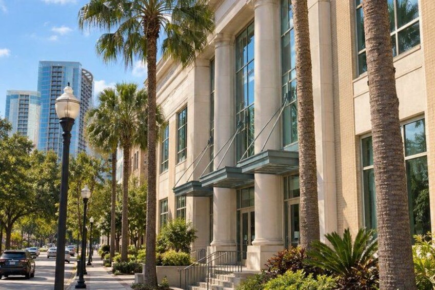 A building with large windows and palm trees, a street with cars, and a clear sky. 5