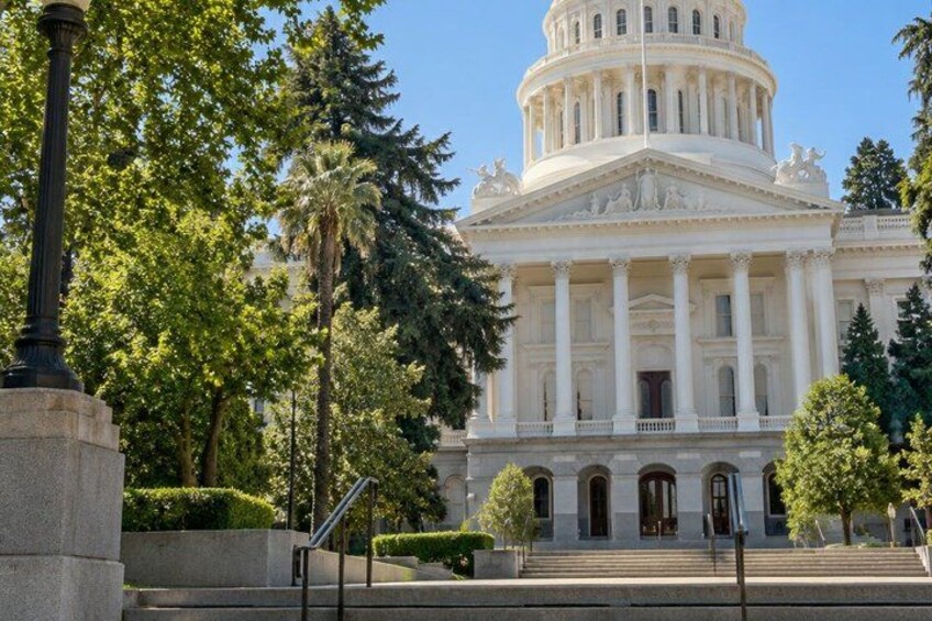 A large neoclassical building with a central dome, surrounded by trees and a paved area. 2