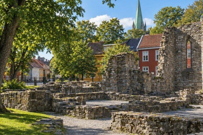 Ancient stone ruins, a church with a green spire, and modern buildings in the background. 5