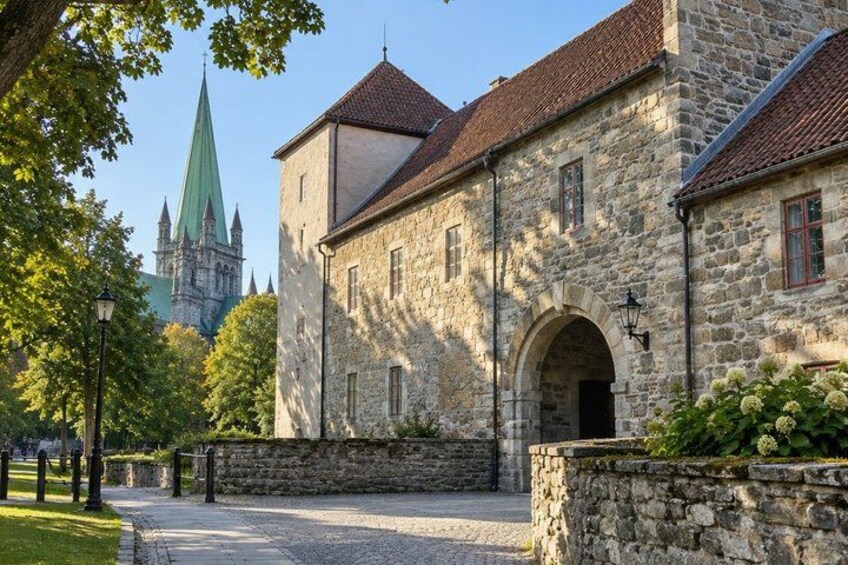 A historic stone building with a green spire in the background. 3