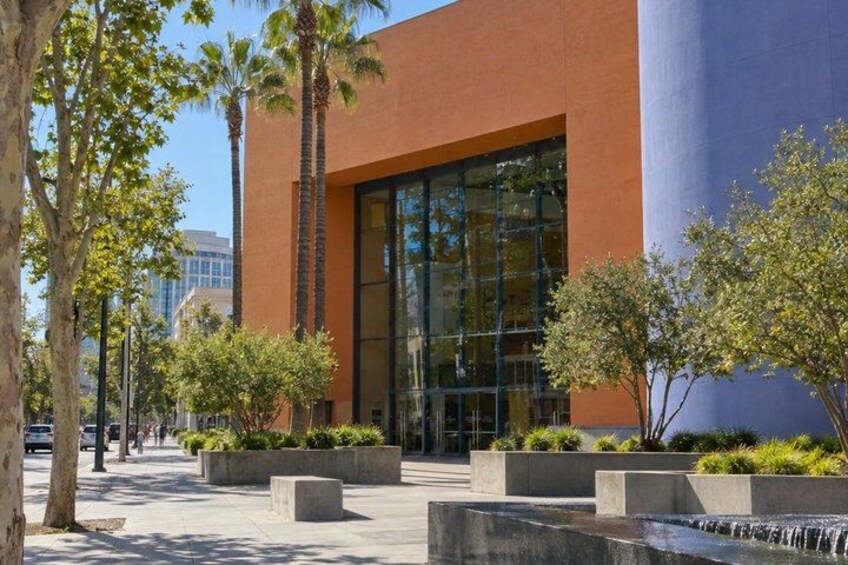 A modern building with large windows, surrounded by trees and a water feature. 3