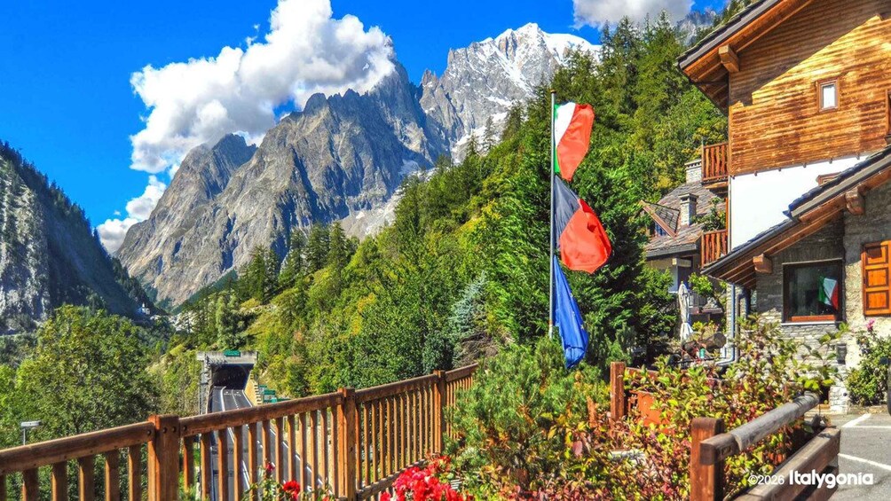 A mountain landscape with a wooden building, a wooden fence, and two flags. 3