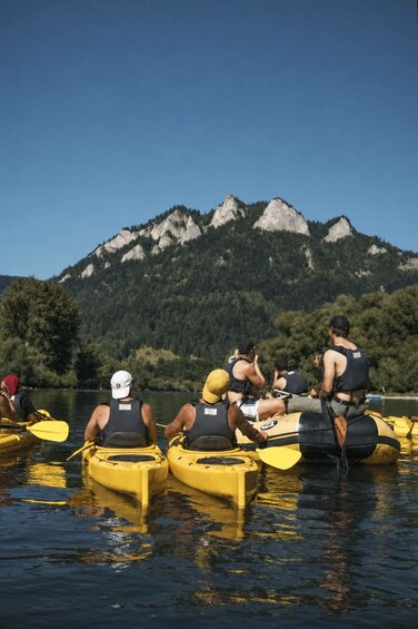 People kayaking on a calm lake with mountains in the background. 4