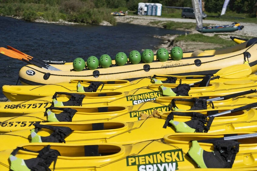 A row of yellow kayaks with helmets and paddles, labeled 'PIENINSKI SPILW.' 3
