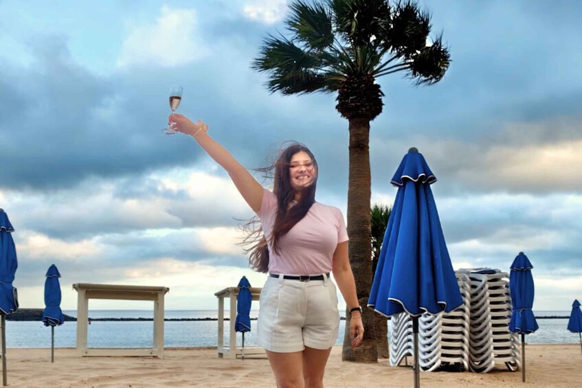 A person taking a selfie on a beach with palm trees and umbrellas in the background. 5