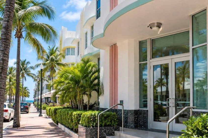 A coastal building with palm trees, a clear sky, and a sidewalk. 1
