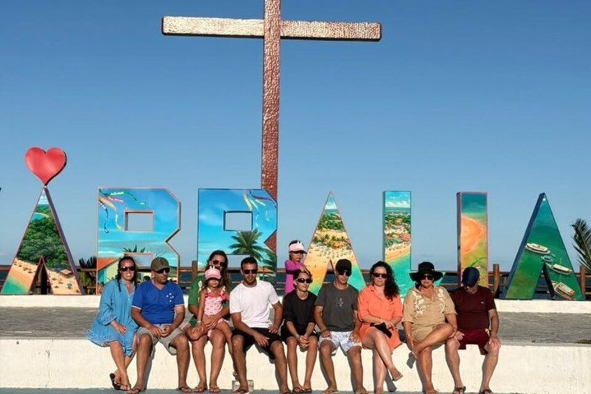 A group of people sitting in front of large letters spelling 'BRAHMA' with a cross behind them. 2