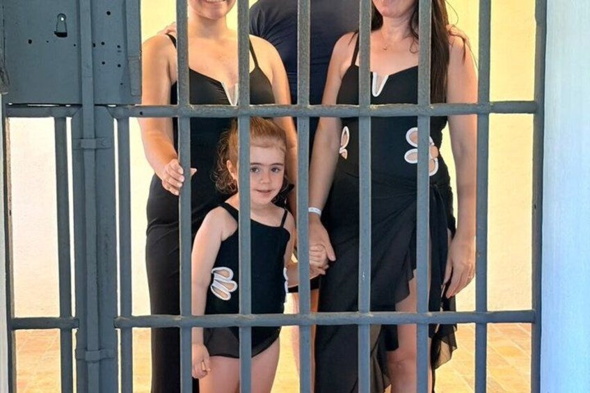A family of four in black attire standing behind a metal gate. 5