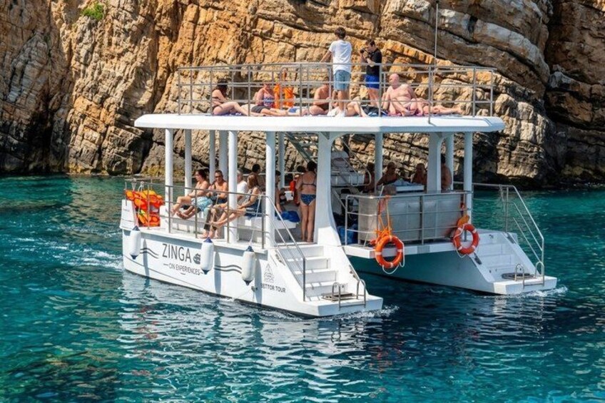 A boat with people on it, surrounded by clear blue water and rocky cliffs. 1