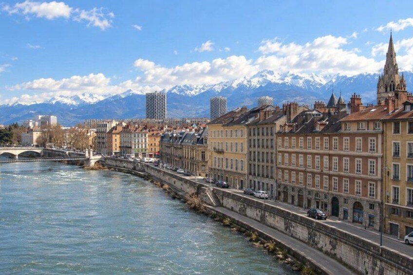 A river with buildings along the banks, a bridge, and mountains in the background. 4
