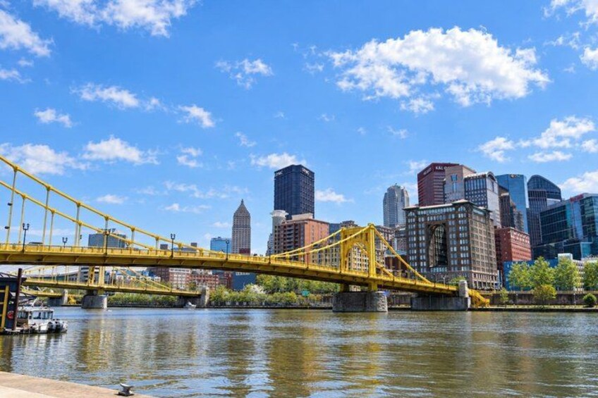 A yellow bridge over a river with a city skyline in the background. 5