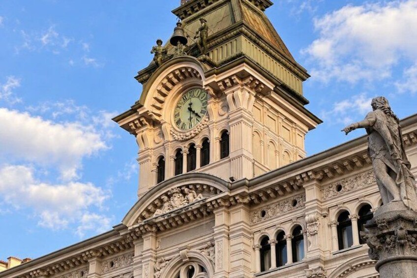 A historic building with a clock tower and a statue. 2