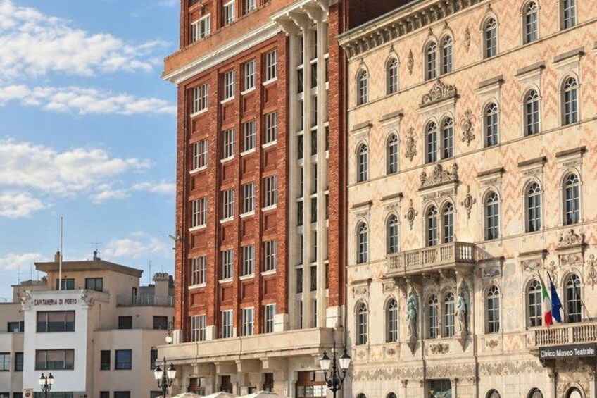 A historic building with ornate architecture, a red brick facade, and a balcony with flags. 4