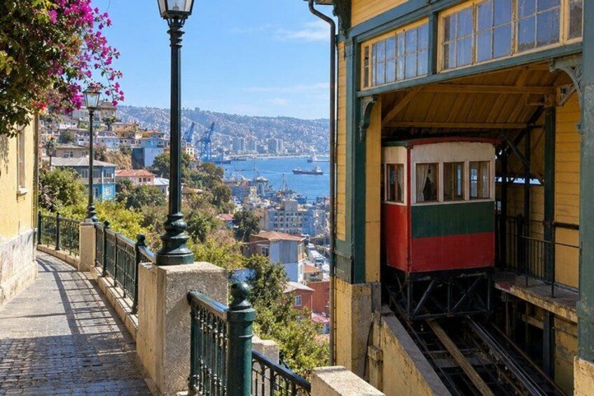 A cable car on a steep incline, overlooking a coastal city with buildings and a harbor. 1