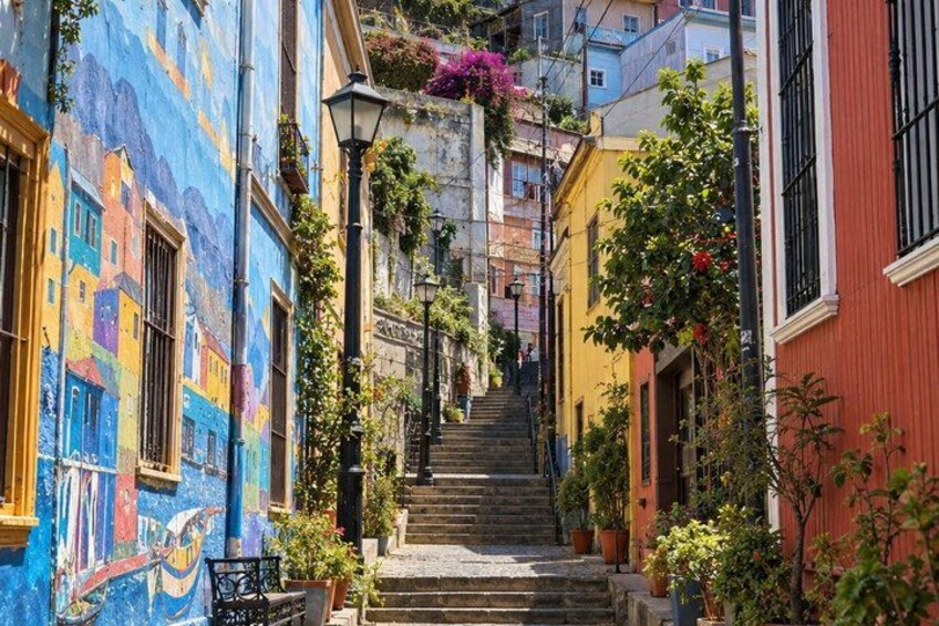 A narrow street with colorful buildings, a staircase, and potted plants. 4