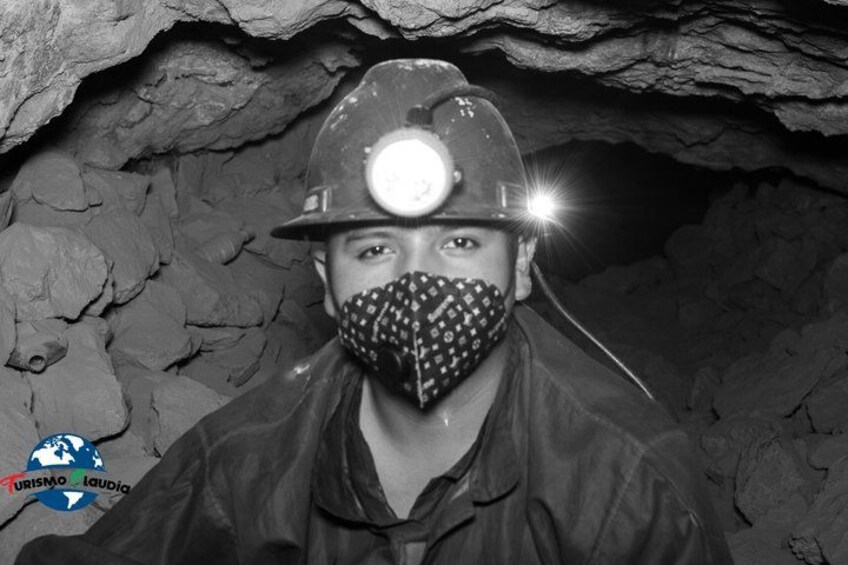 A person wearing a hard hat and a face mask in a cave with rocky walls. 5