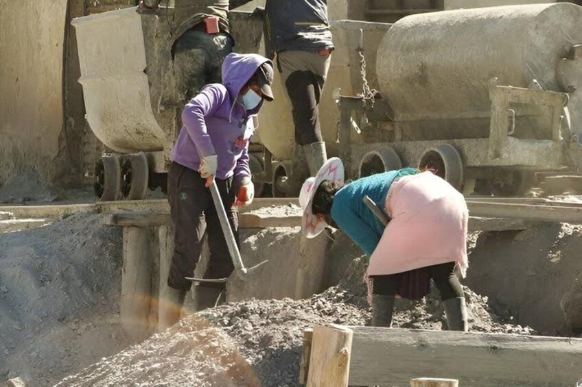 Workers at a construction site using tools to dig and move earth. 3