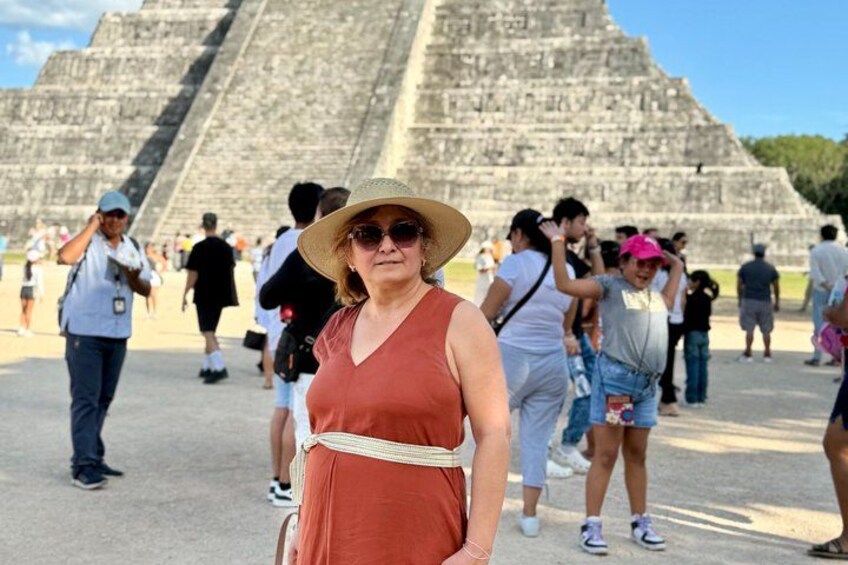 A person in a red dress and straw hat standing in front of a large pyramid structure. 3