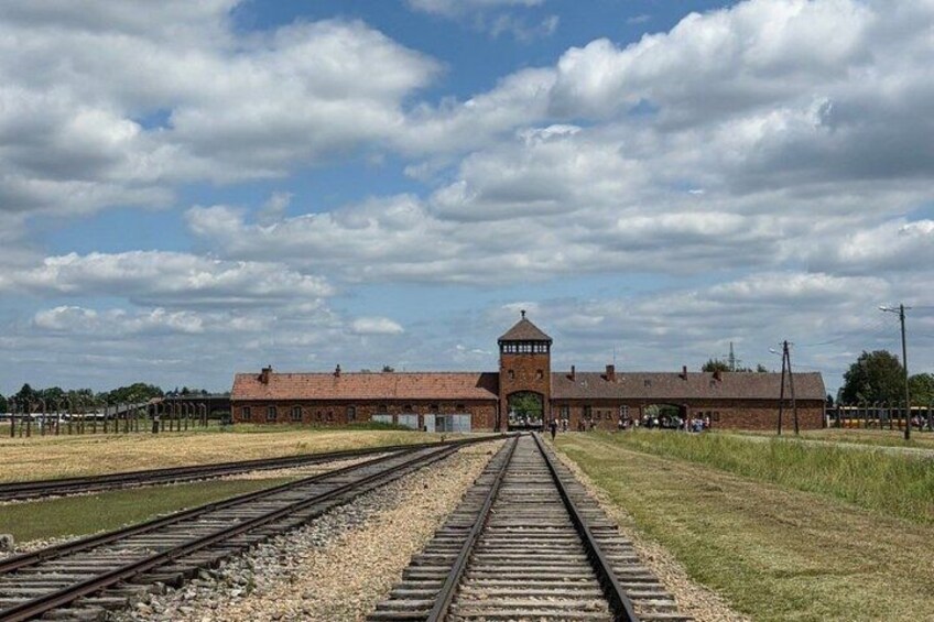 A railway station with tracks, a brick building, and a tower. 3