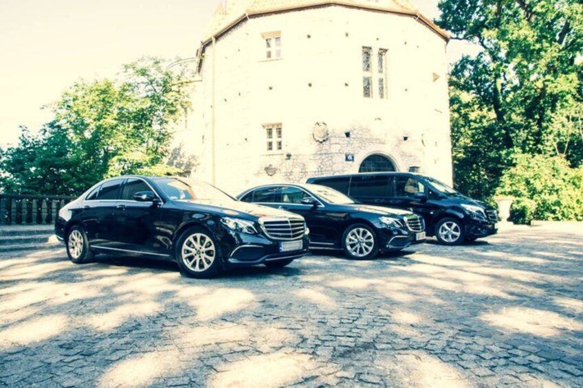 Three black cars parked in front of a building with a stone facade. 1