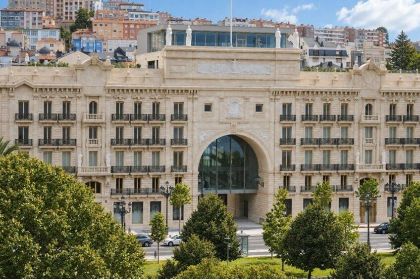 A large, ornate building with a central archway, surrounded by lush green trees and a clear blue sky. 5