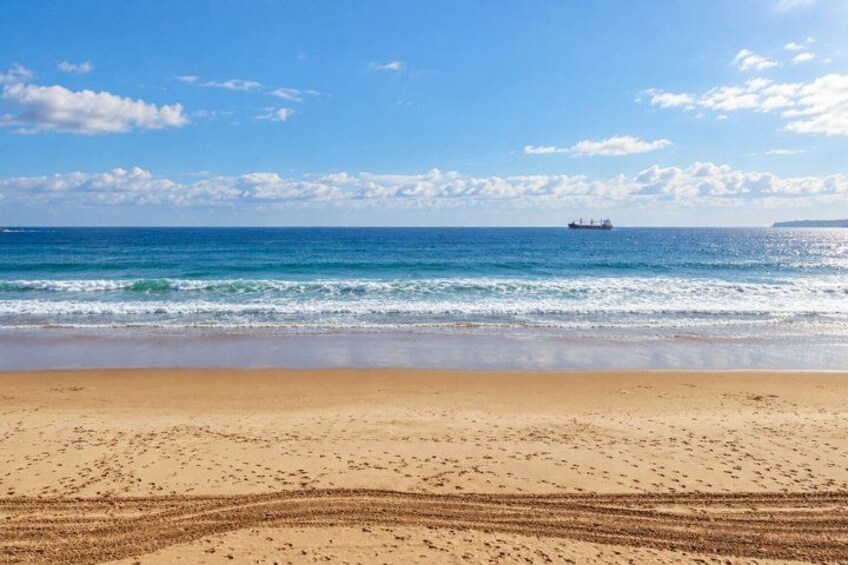A beach with a ship in the distance and a clear sky. 4