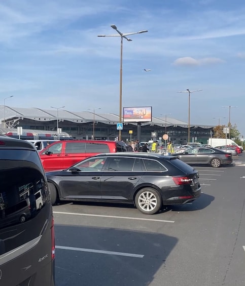 A parking lot with cars, a pedestrian crossing sign, and a building with a curved roof. 2