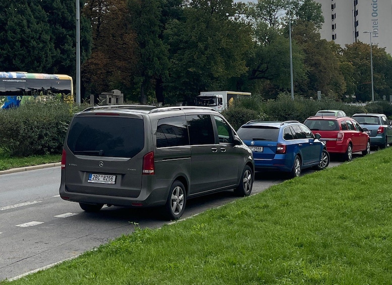 A parked van and several cars on a road with grass on the side. 5