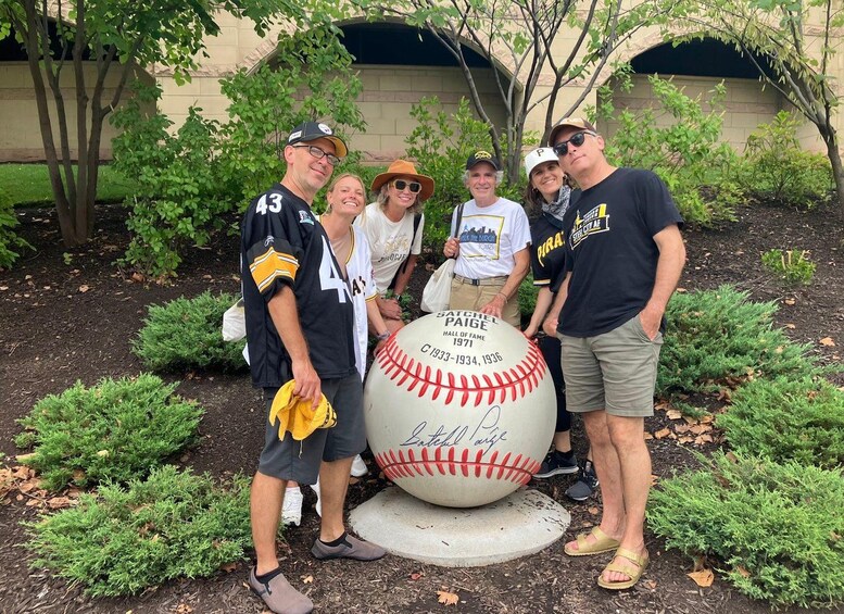 A group of people posing with a baseball statue. 4