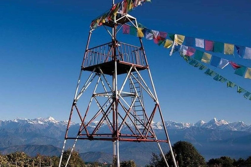 Une tour métallique dotée d’une rambarde métallique, entourée d’un paysage montagneux et surplombant un ciel bleu dégagé. 1