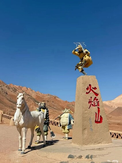 Une statue d’un guerrier, posée sur un piédestal, avec un cheval au premier plan et un paysage désertique en arrière-plan. 2