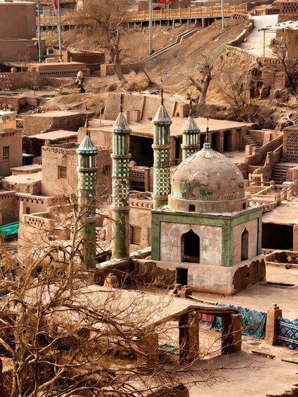 Un bâtiment traditionnel doté d’un dôme et de minarets, entouré d’un paysage aride à la végétation clairsemée. 1