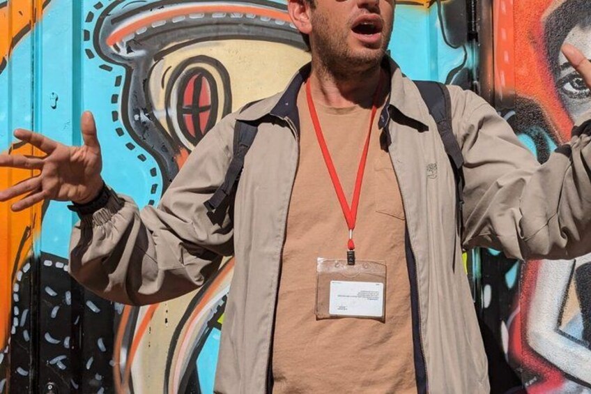 A person standing in front of a colorful mural with abstract designs. 3