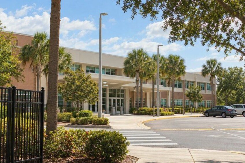 A modern building with a parking lot, palm trees, and a clear sky. 5