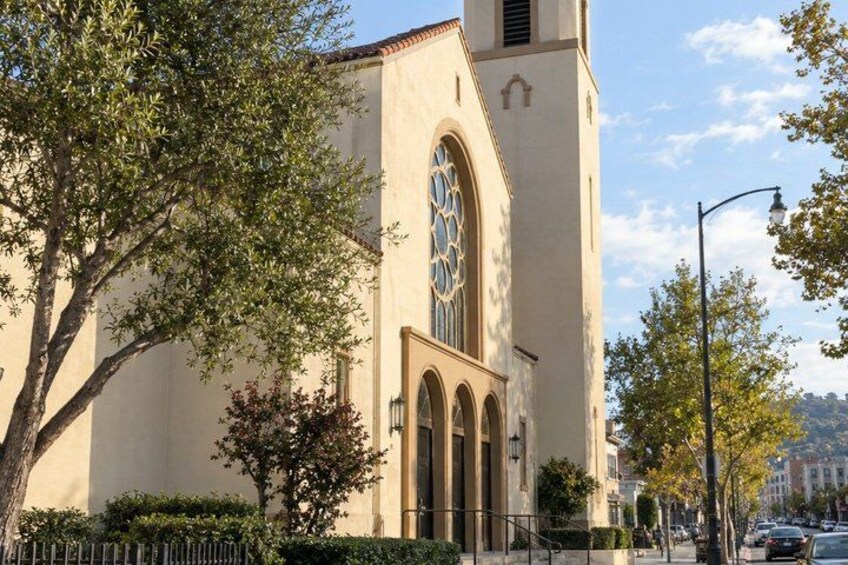 A church with a tall bell tower, arched windows, and a tree in the foreground. 3