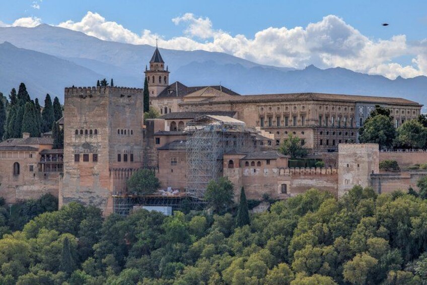 A historic castle with a tower, surrounded by a forest and mountains in the background. 3