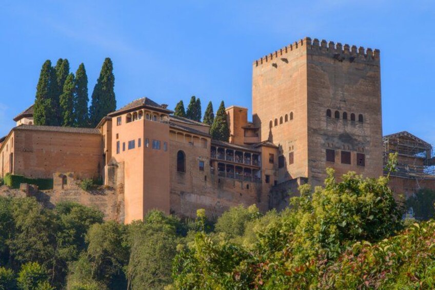 A historic castle with a prominent tower, surrounded by lush greenery and trees. 1