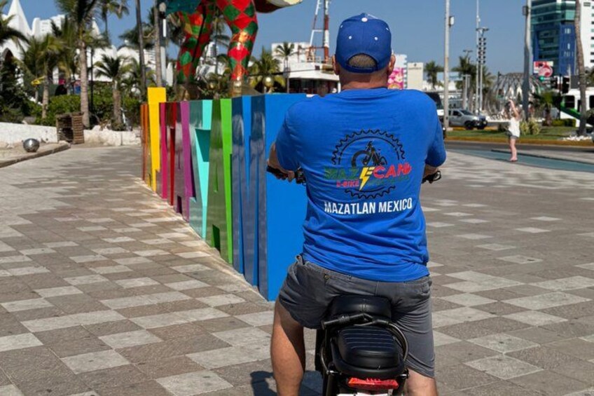 A person riding a motorcycle on a paved path with colorful vertical panels. 2