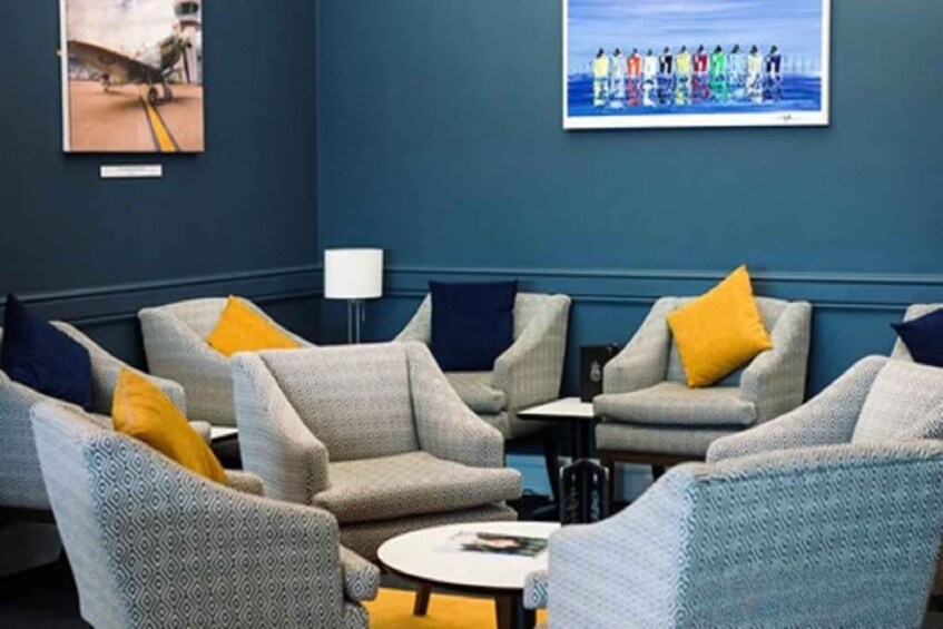 A lounge area with grey sofas and yellow cushions, a small round table, and two wall-mounted lamps. 2