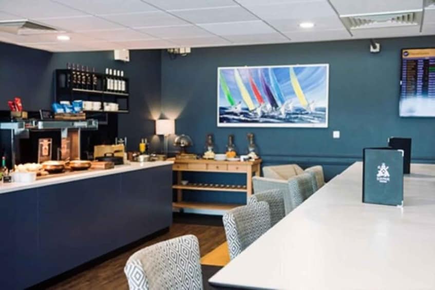 A modern bar area with a counter, seating, and a large sailboat painting on the wall. 1