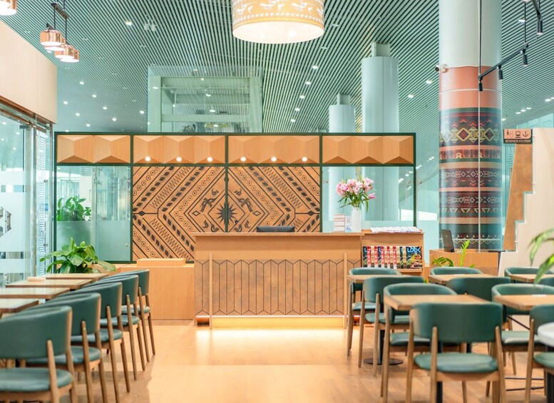 A modern interior with a wooden reception desk, green chairs, and a patterned wall. 2