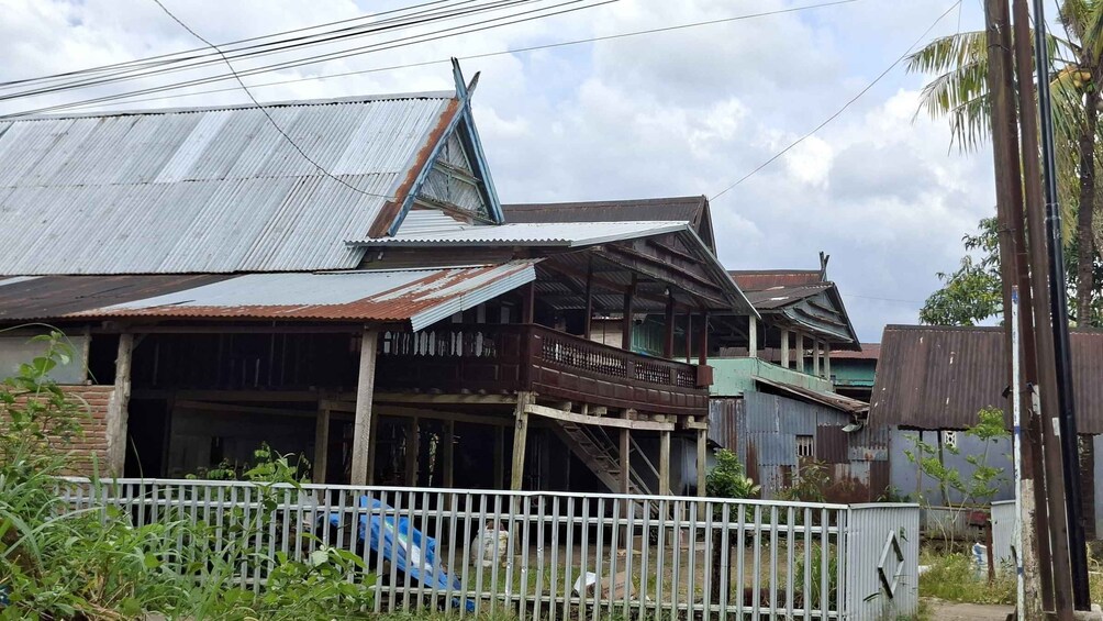 A dilapidated house with a corrugated metal roof and wooden balcony. 5
