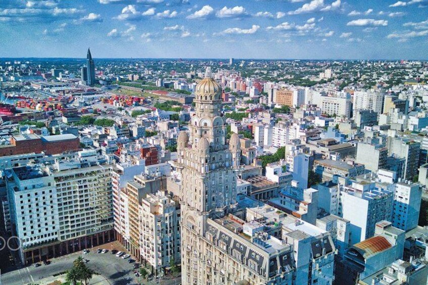 A cityscape with a prominent historic building with a dome, surrounded by modern high-rise buildings. 2