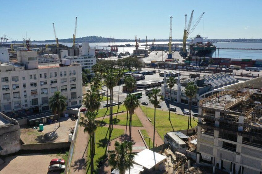 A port with ships, cranes, and a large building. 1