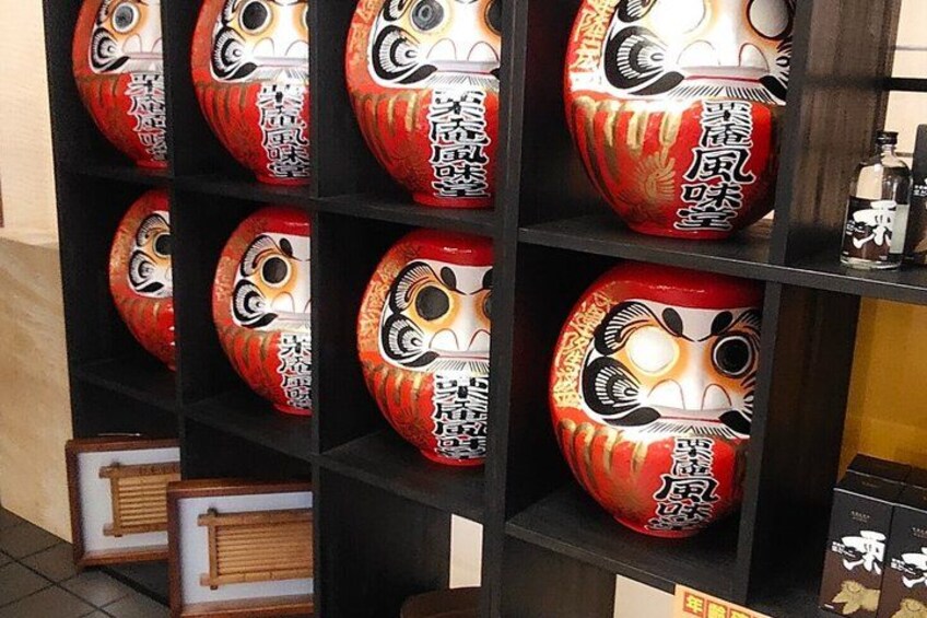 A shelf with red and white Japanese dolls with black facial features. 3