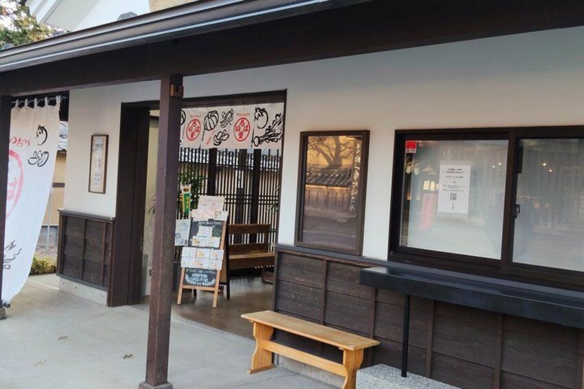 A traditional Japanese building with a wooden bench outside, a signboard, and a window with a notice. 5