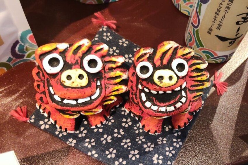 Two red and black plush toys with large eyes and a smiling face on a patterned cloth. 4