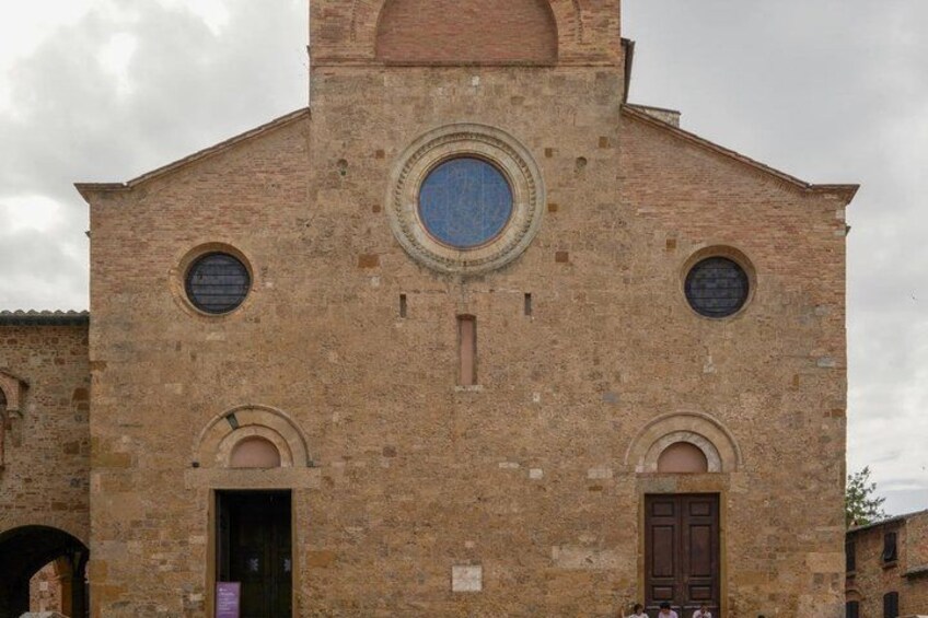 A historic stone building with a central circular window, two smaller circular windows, and a wooden door. 5