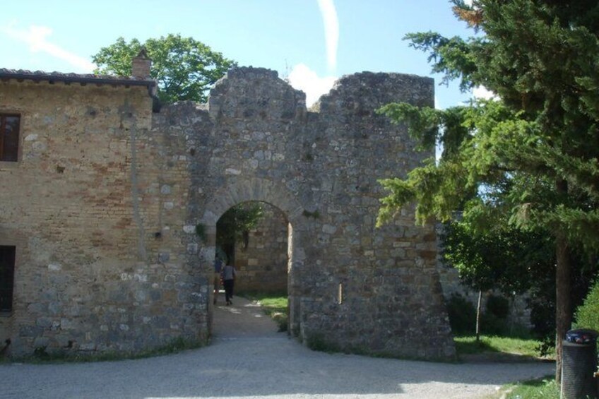 A stone archway leading into a building, surrounded by trees and a clear sky. 4